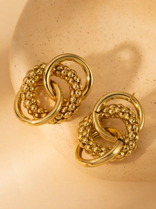 Close-up of gold layered hoop earrings with polished and textured interlocking ring details