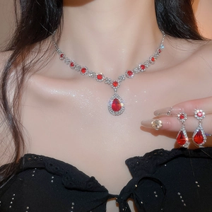 Detailed view of silver jewelry set with red drop-shaped gemstones on a female model