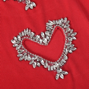 Close-up of red ribbed T-shirt fabric featuring heart-shaped rhinestone embellishments