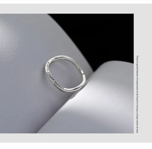Macro shot of silver S925 ring engraved with Smooth Waters Run Deep on soft white curve