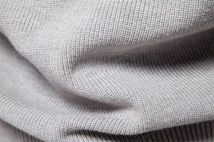 Close-up of grey knit fabric texture showing the soft fibers of the men's sweater