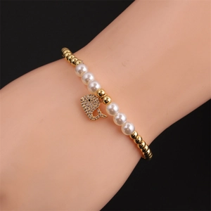 Elastic pearl and gold bead bracelet with zircon dolphin pendant on a woman wrist