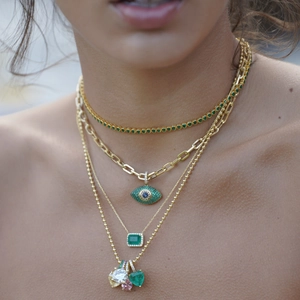 Layered gold necklaces with emerald zircon pendants and evil eye charm on model