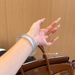 Détail d'un bracelet jonc rond et translucide en œil de chat porté au poignet, design épuré