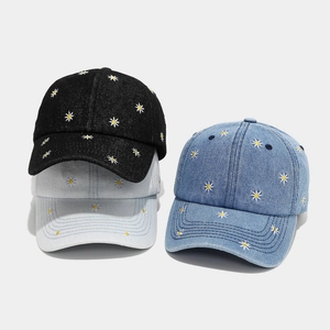 Denim baseball caps with white daisy embroidery in black, medium blue, and light blue colors