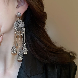 Close-up of vintage silver earrings featuring layered hollow discs and metallic tassel bells