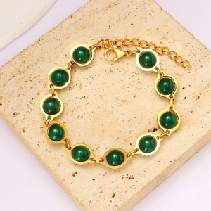 Detailed view of round green agate stones bezel-set in a gold chain bracelet