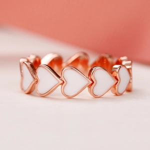 Détail macro de la bague coeur en or rose avec émail blanc au style romantique