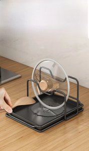 Detail of matte black carbon steel pot lid holder with removable drip tray on wooden desk