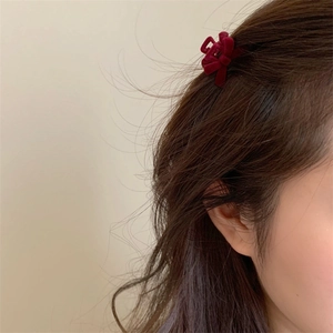 Close-up of a burgundy velvet bow hair claw clip styled on dark hair for side accents