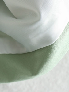 Close-up of white and mint green woven fabric texture on a V-neck blazer jacket