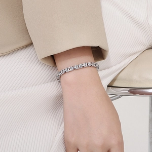 Detailed view of heavy titanium steel link bracelet on model wearing beige suit