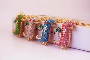 Détail de quatre porte-clés dinosaures en cristal coloré en vert, argent, bleu et rose