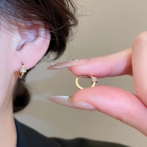 Detail of 18k gold plated hoop earring with sparkling zircon cylinder charm on a model