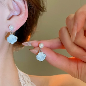 Close-up of butterfly wing silver earring with gradient pearl drop on female ear