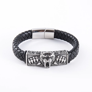 Macro shot of men's black braided leather bracelet featuring a silver lion head charm
