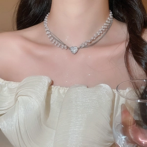 Detail of double-layer necklace with white pearls, silver chain, and diamond heart pendant