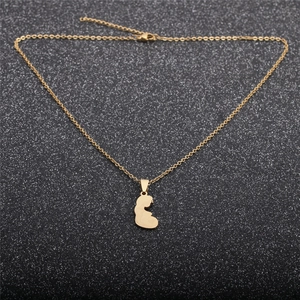 Detailed view of a gold pregnant woman silhouette pendant on a black glitter background