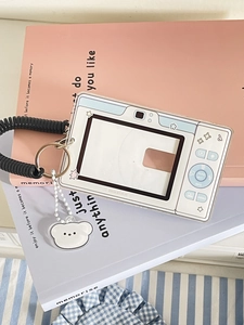 Close-up of white camera-shaped acrylic photocard holder with bear charm and spiral lanyard