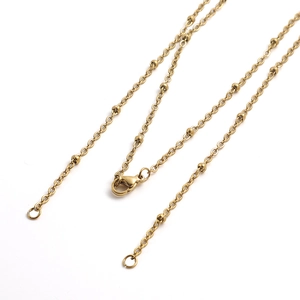 Detail of golden stainless steel bead chain necklace showing clasp and metal texture