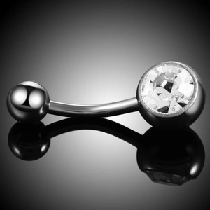 Macro view of silver belly button ring with large sparkling crystal on black reflection