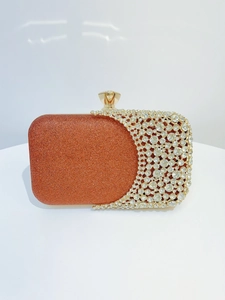 Detail of orange glitter evening clutch featuring sparkling rhinestones and gold clasp