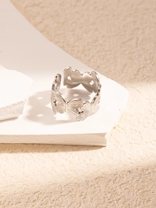 Detailed shot of a silver butterfly textured open ring on a decorative white stone