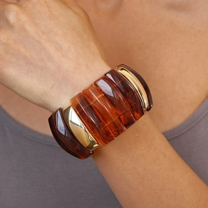Detail of amber translucent resin cuff bracelet with gold metal dividers on wrist