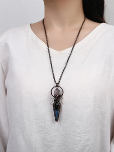Primer plano de collar retro de bronce con amatista y colgante de luna usado por una modelo