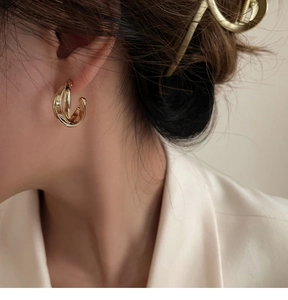 Gros plan de boucles d'oreilles créoles dorées géométriques sur modèle pour un look épuré