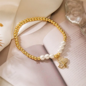 Détail du bracelet en perles dorées avec perles blanches et pendentif feuille en zircon