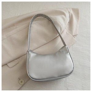Detail of silver crescent moon bag with metallic texture on a beige blazer