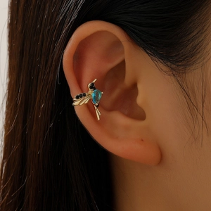 Detail of a gold hummingbird ear cuff with blue zircon and black crystal stones