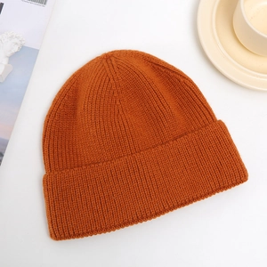 Close-up of bright orange knitted beanie with dense texture and warm material