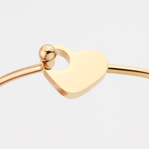Polished gold titanium steel open bangle featuring a unique heart-shaped clasp detail