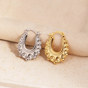 Detalle de pendientes en forma de U huecos en oro y plata con patrones grabados