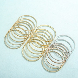 Dettaglio di bracciali rigidi minimalisti in acciaio lucido nei colori oro e argento