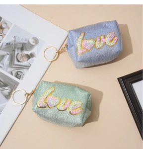 Close-up of mini glitter coin purses with sequin love lettering and gold keychains