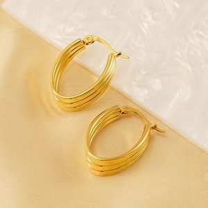 Boucles d'oreilles ovales multicouches en or 18k sur un fond élégant en soie