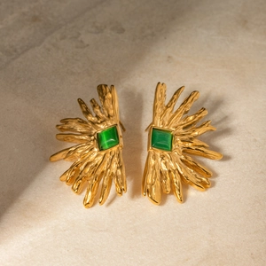 Detail of 18k gold sunburst earrings with green cat eye stone on stone background