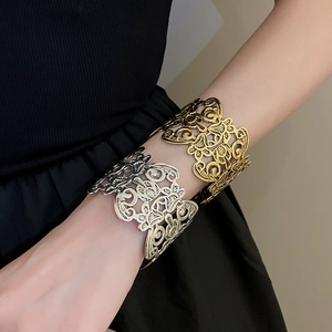 Detailed close-up of hollow flower cut-out metal cuffs in gold and silver finish