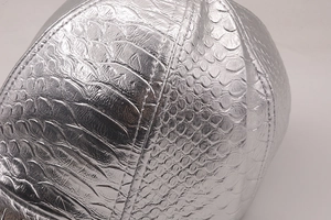 Détail macro de la texture crocodile argentée sur une casquette en cuir PU tendance