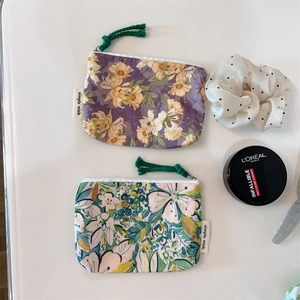 Detailed view of floral canvas coin purses with zippers and brand tags on white background