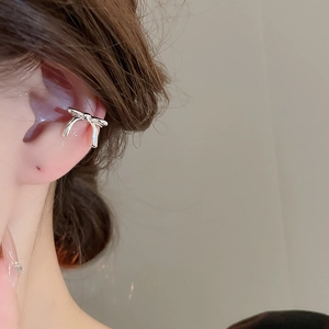 Close-up of bow-shaped silver ear cuff with pearls worn on the ear for a stylish look