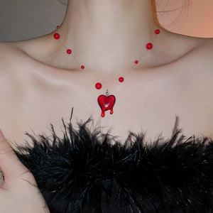Detail view of a red heart pendant necklace with liquid drop effect on a model's collarbone