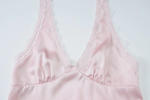 Detail of pink satin sleepwear with white lace trim and elegant deep V-neckline pleats