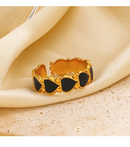 Macro view of adjustable gold-finish ring with black enamel heart pattern on silk