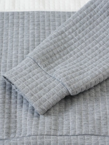 Close-up of light gray quilted texture and ribbed cuffs on a casual men hoodie
