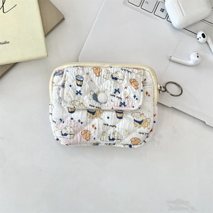 Quilted white mini storage bag with cute puppy prints and metal keychain on a desk
