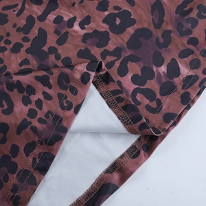 Détail du tissu à imprimé léopard montrant la texture en maille et l'ourlet cousu